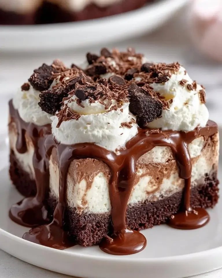 Frozen brownie ice cream cake with layers of brownie and ice cream topped with chocolate sauce.